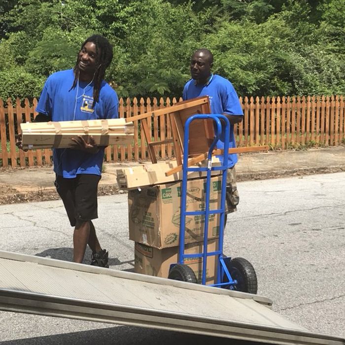 Movers carrying boxes from a rental truck into a Georgia home